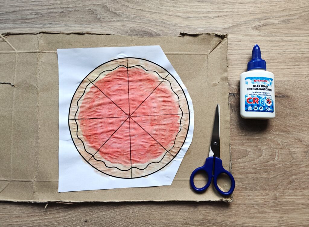 Prawie gotowy spód do pizzy. Pomalowana kolorowanka została przyklejona do kartonu.